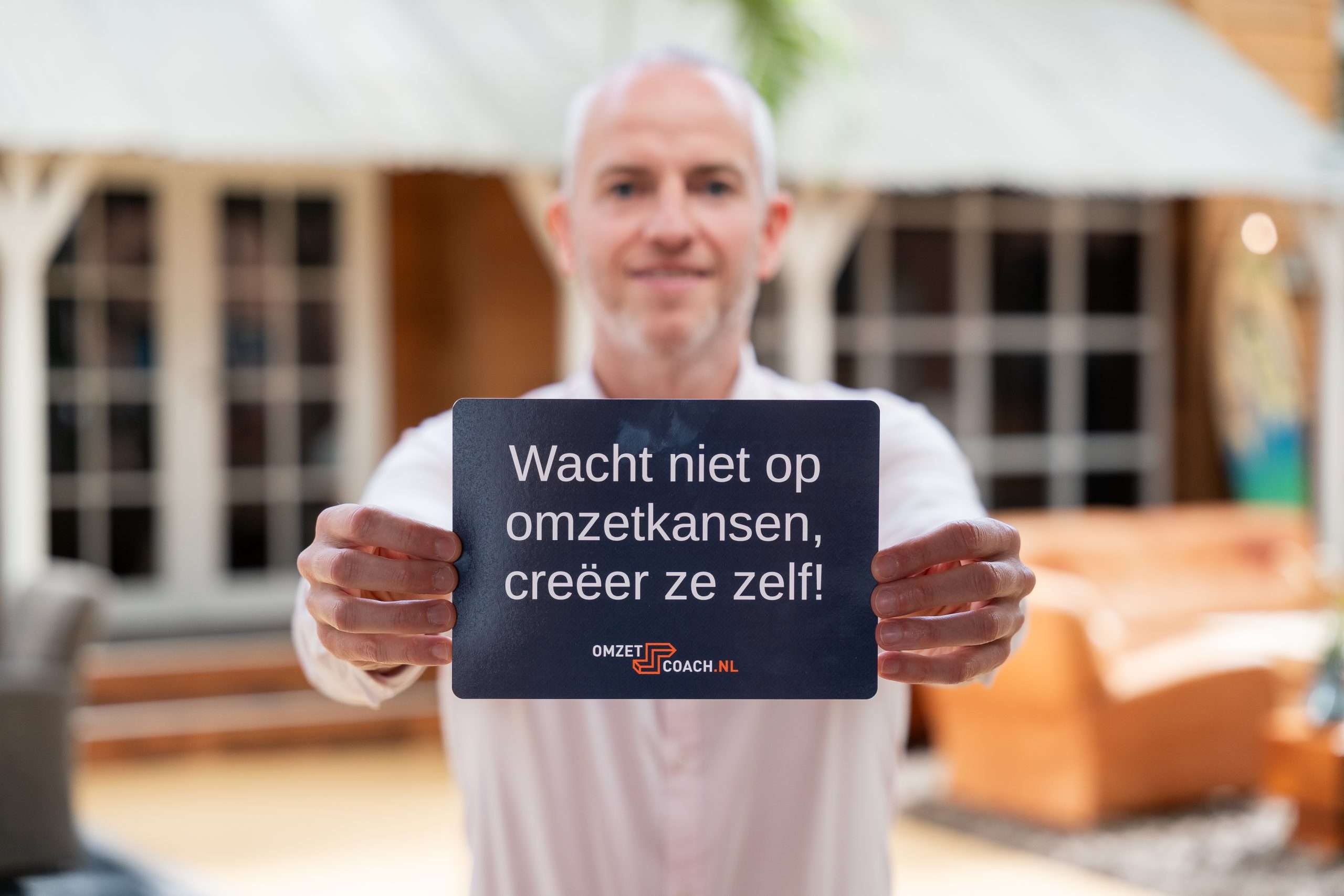 Mark Vos met een flyer in zijn handen waarop staat dat je niet moet wachten op omzetkansen, maar ze zelf moet creëren. Hij legt uit hoe je via LinkedIn klanten kunt binnenhalen.